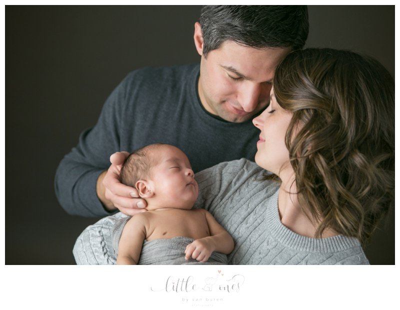 Loving parents hold their baby during his newborn portrait session.